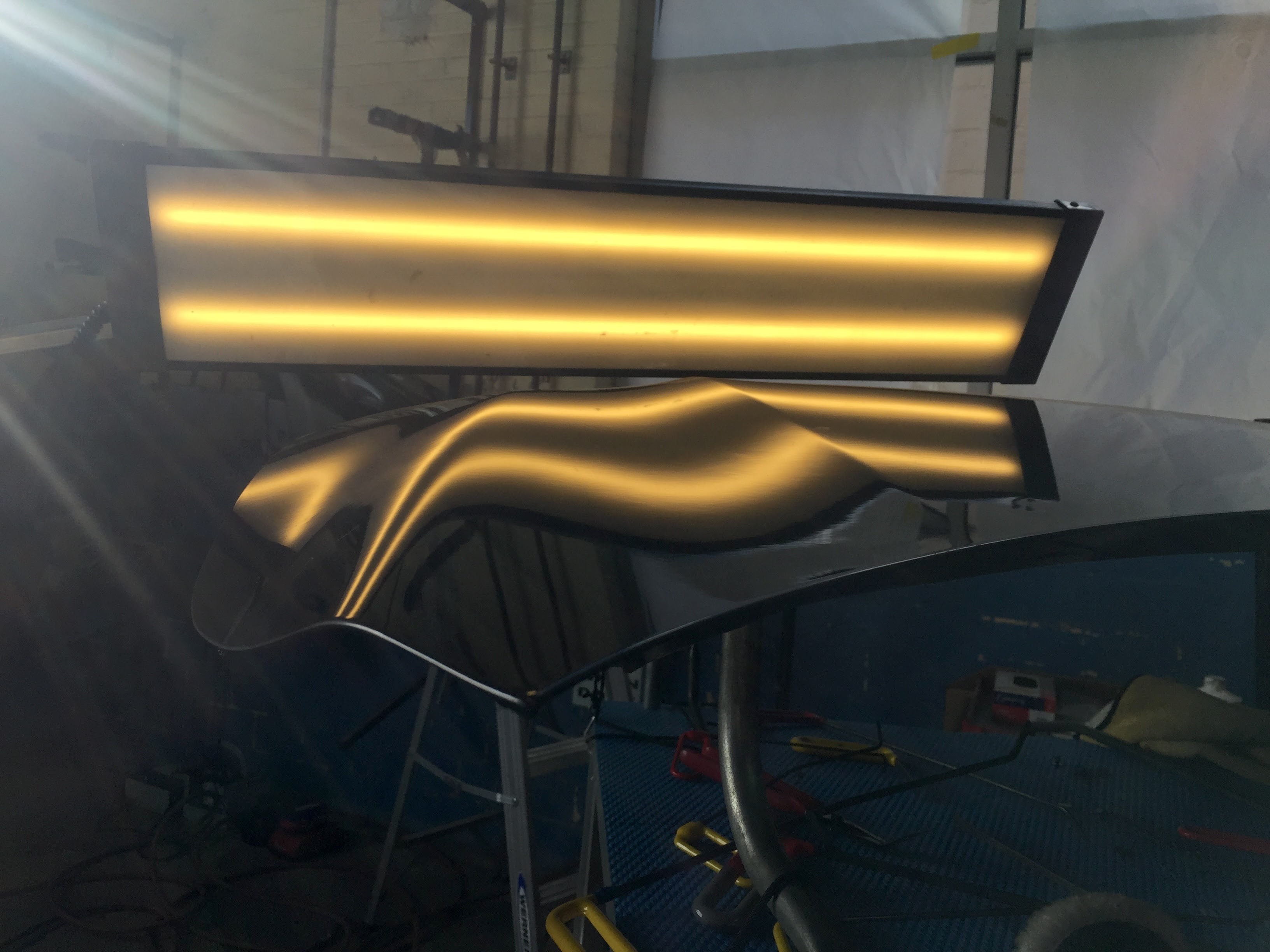 Repaired vehicle panel with smooth reflections under an inspection light after paintless dent repair