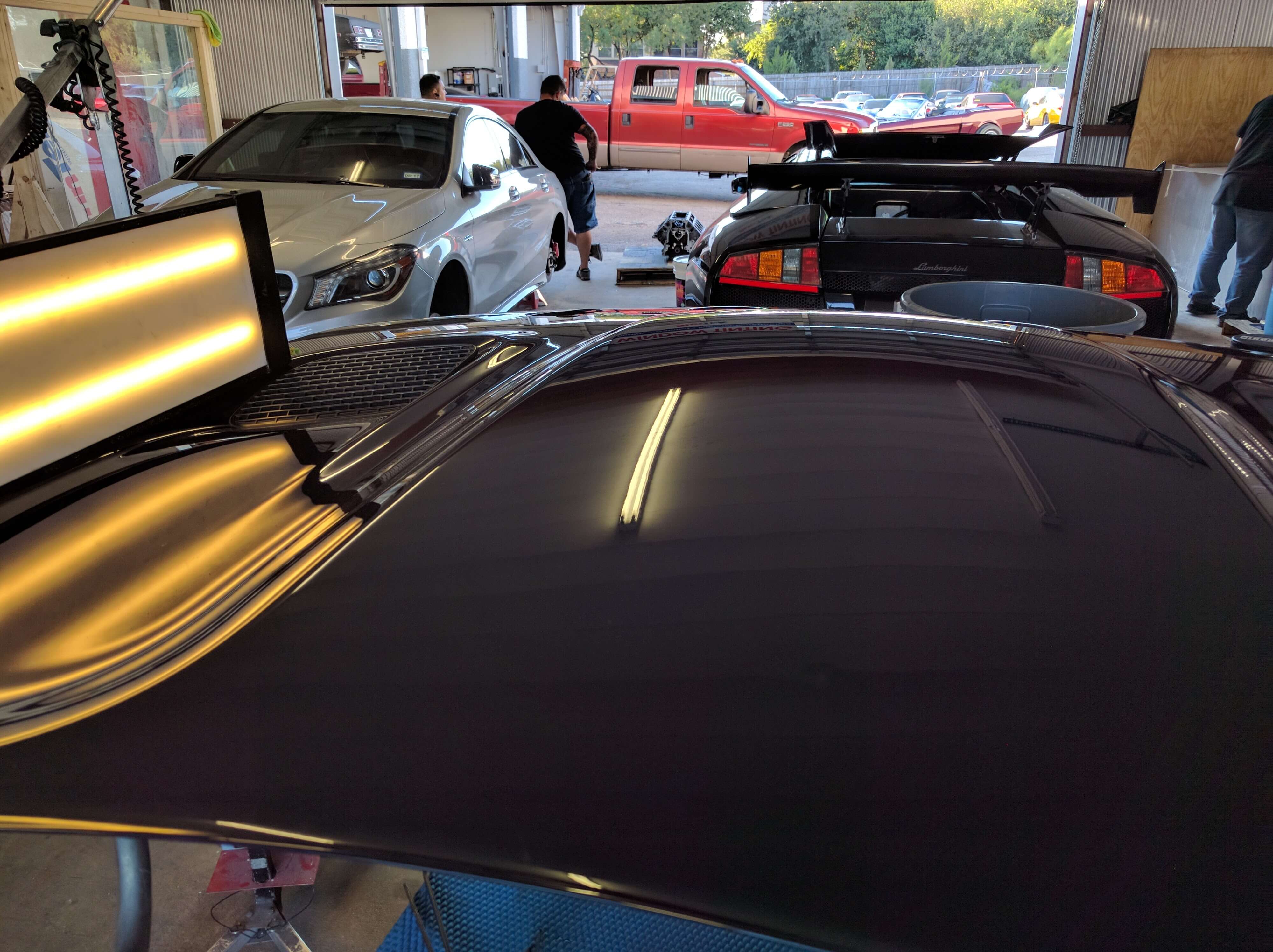 Paintless dent repair setup with inspection lights reflecting across a vehicle hood